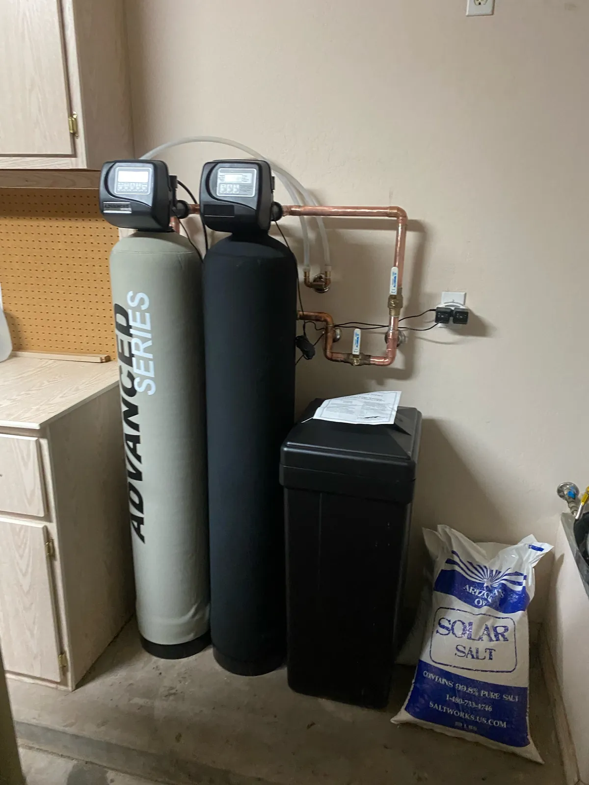 Dual-tank water softener and carbon filter system with brine tank and copper bypass installed in a garage by Max Plumbing in Surprise, AZ